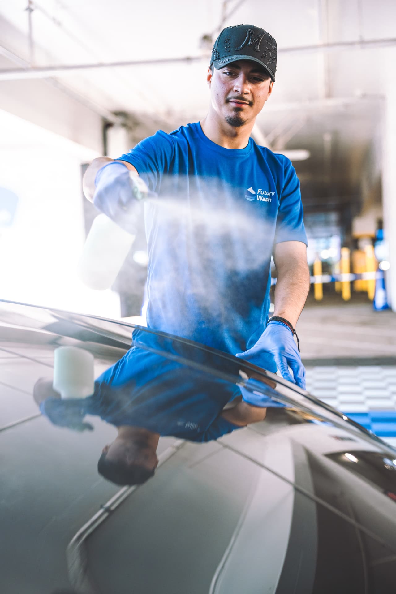 Future Wash technician washing a car's exterior in an airport parking lot